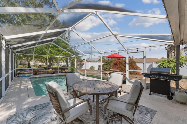 view of patio featuring glass enclosure, grilling area, and a fenced backyard