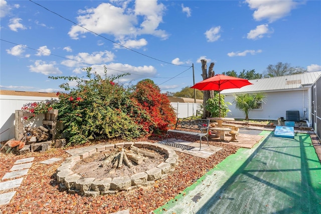 view of yard featuring central AC, an outdoor fire pit, a patio, and a fenced backyard