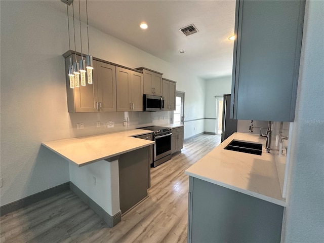 kitchen with light wood finished floors, stainless steel appliances, visible vents, a sink, and a peninsula