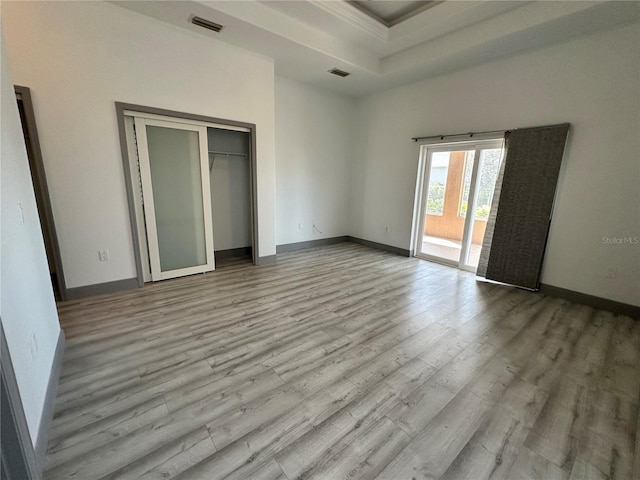 unfurnished bedroom featuring a raised ceiling, visible vents, wood finished floors, access to outside, and baseboards