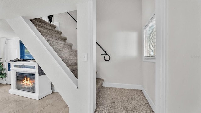 staircase featuring a multi sided fireplace and baseboards