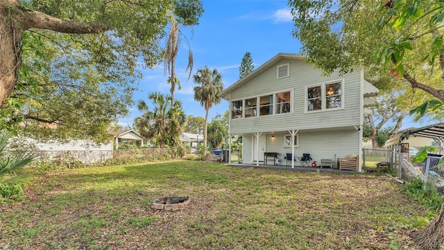 back of house featuring a yard, an outdoor fire pit, a patio area, and a fenced backyard