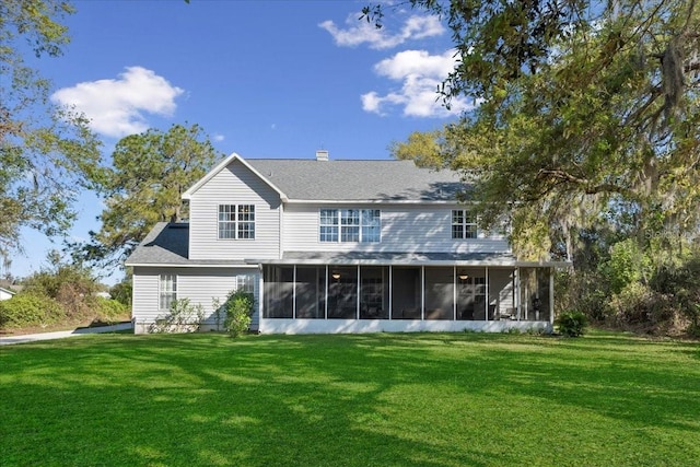 rear view of house with a lawn, a chimney, and a sunroom