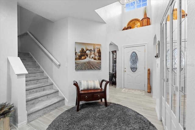 foyer with stairway, wood tiled floor, arched walkways, and baseboards