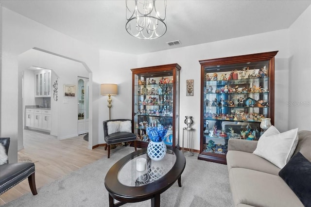 living room featuring light wood-style floors, arched walkways, visible vents, and baseboards