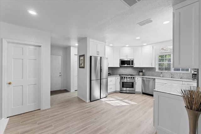 kitchen featuring light countertops, visible vents, backsplash, appliances with stainless steel finishes, and light wood-style floors