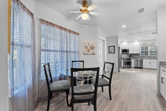 dining area featuring light wood-type flooring, visible vents, and a ceiling fan