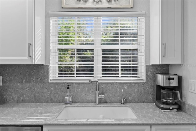 room details with light stone counters, white cabinetry, decorative backsplash, and a sink