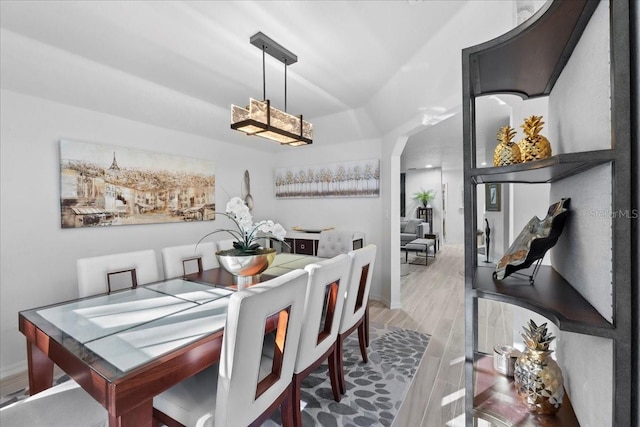 dining space with arched walkways and wood finished floors