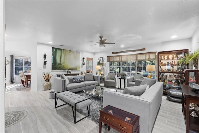 living room with a textured ceiling, recessed lighting, a ceiling fan, and light wood-style floors