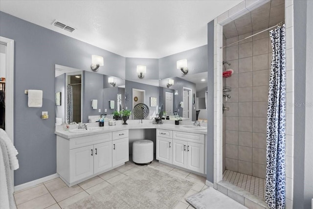 bathroom featuring tiled shower, tile patterned flooring, vanity, and visible vents