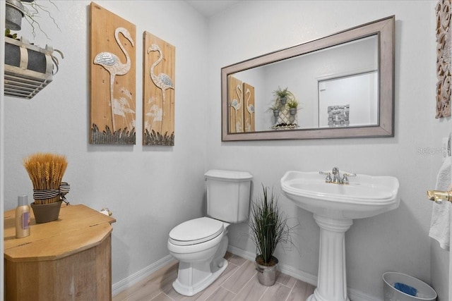 bathroom with a sink, toilet, and baseboards