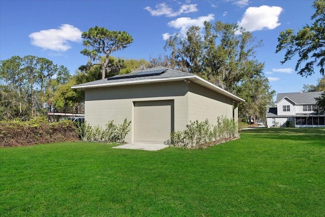 exterior space with a garage, roof mounted solar panels, and a lawn