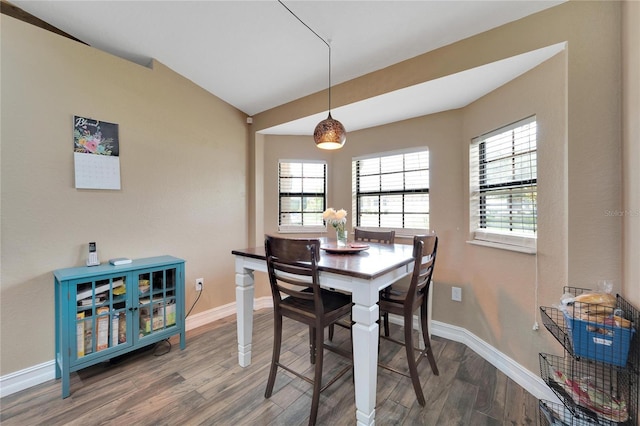 dining area featuring baseboards, vaulted ceiling, and wood finished floors