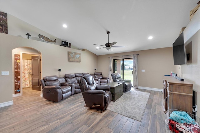 living room with arched walkways, ceiling fan, baseboards, vaulted ceiling, and light wood finished floors