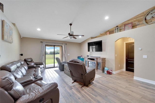 living area with arched walkways, light wood-style flooring, vaulted ceiling, ceiling fan, and baseboards