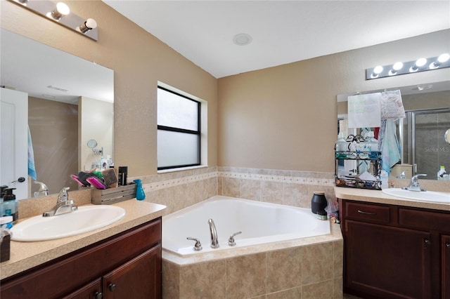 full bath featuring a garden tub, two vanities, a sink, and a shower stall