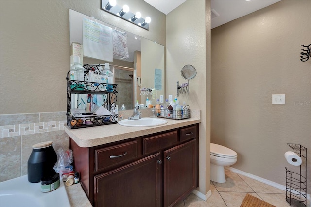 bathroom with tile patterned flooring, toilet, vanity, baseboards, and a stall shower