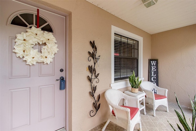 entrance to property featuring covered porch, stucco siding, and visible vents