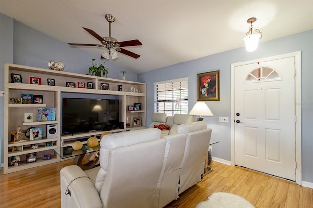 living room with baseboards, light wood-type flooring, ceiling fan, and vaulted ceiling