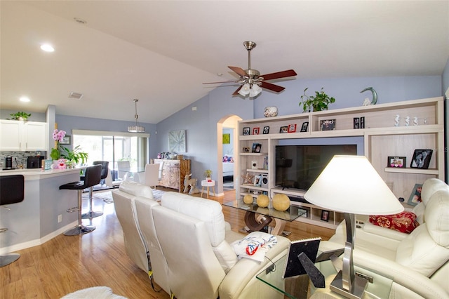 living room featuring visible vents, arched walkways, light wood finished floors, ceiling fan, and vaulted ceiling