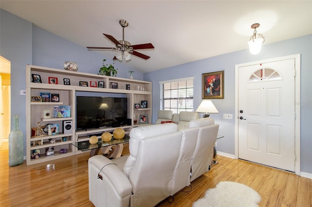 living room with baseboards, wood finished floors, a ceiling fan, and vaulted ceiling