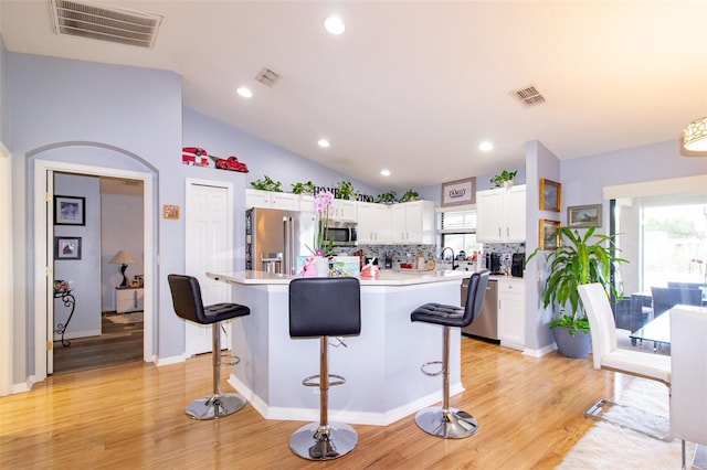 kitchen featuring visible vents, appliances with stainless steel finishes, white cabinetry, and a kitchen bar