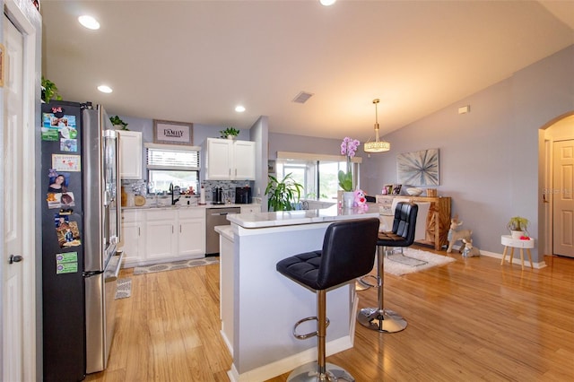 kitchen with arched walkways, a sink, vaulted ceiling, white cabinets, and appliances with stainless steel finishes