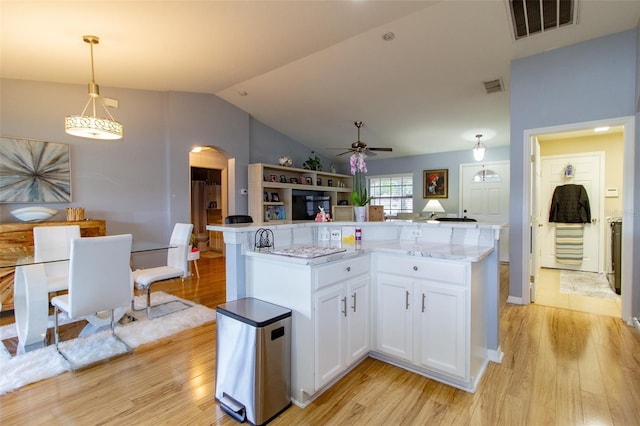 kitchen featuring visible vents, open floor plan, hanging light fixtures, light wood-style floors, and arched walkways