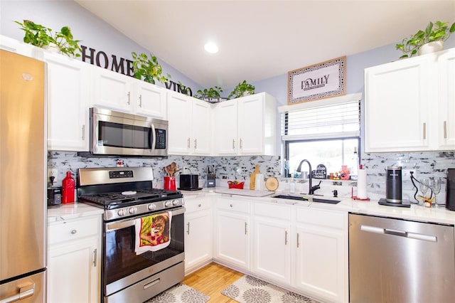 kitchen with a sink, stainless steel appliances, backsplash, and white cabinets