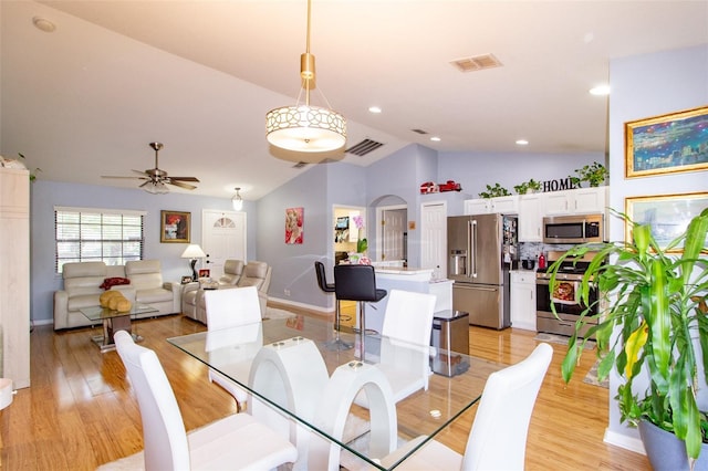 dining area with arched walkways, visible vents, and light wood finished floors