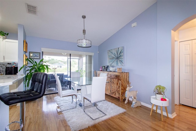 dining space featuring light wood-style floors, arched walkways, visible vents, and baseboards