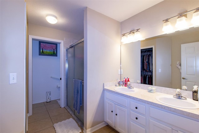 full bath featuring tile patterned floors, a shower stall, double vanity, and a sink