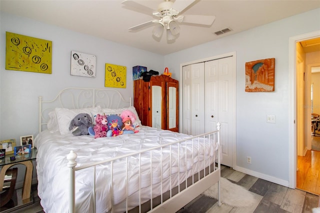 bedroom with wood finished floors, visible vents, baseboards, ceiling fan, and a closet