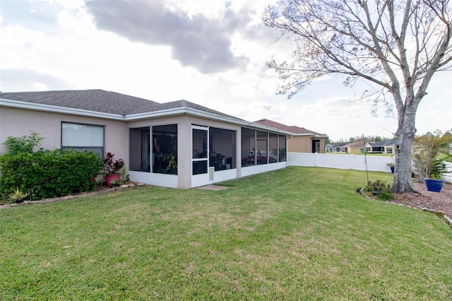 back of property with fence, a yard, a sunroom, a shingled roof, and stucco siding