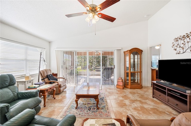 living area with lofted ceiling, light tile patterned floors, a wealth of natural light, and a ceiling fan