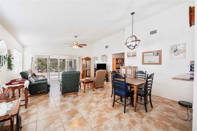 dining space with ceiling fan with notable chandelier, high vaulted ceiling, visible vents, and baseboards