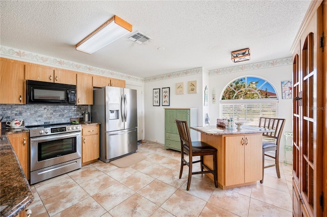 kitchen featuring tasteful backsplash, visible vents, stainless steel appliances, a textured ceiling, and a kitchen bar