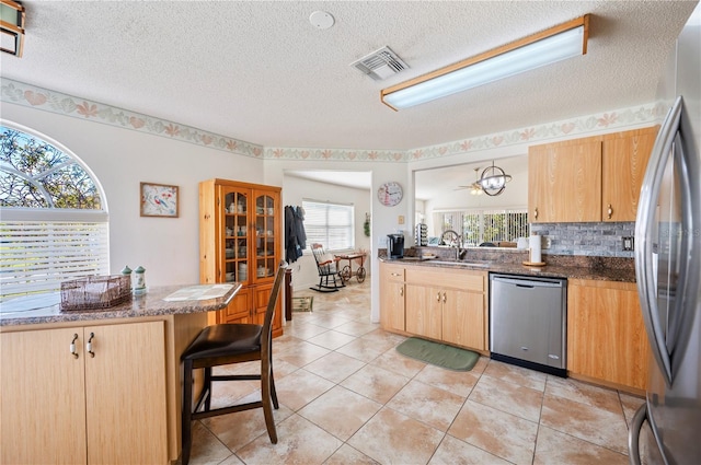 kitchen with stainless steel appliances, visible vents, decorative backsplash, light brown cabinetry, and a sink