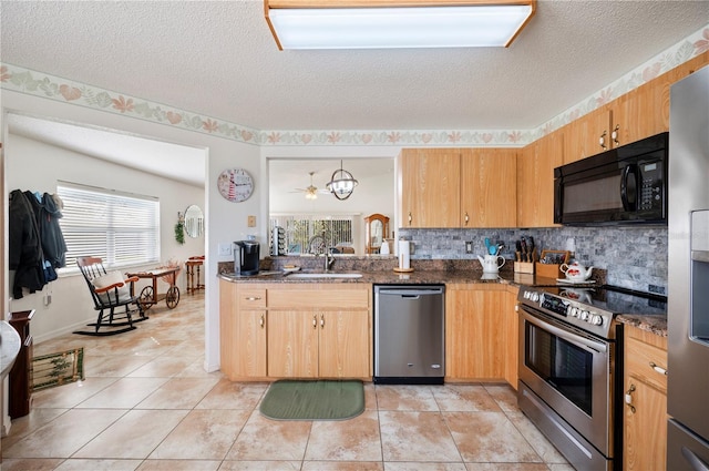 kitchen with tasteful backsplash, appliances with stainless steel finishes, light tile patterned flooring, a sink, and dark stone counters