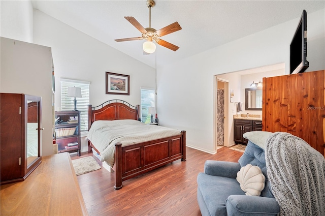 bedroom featuring ensuite bathroom, a ceiling fan, baseboards, vaulted ceiling, and light wood-style floors