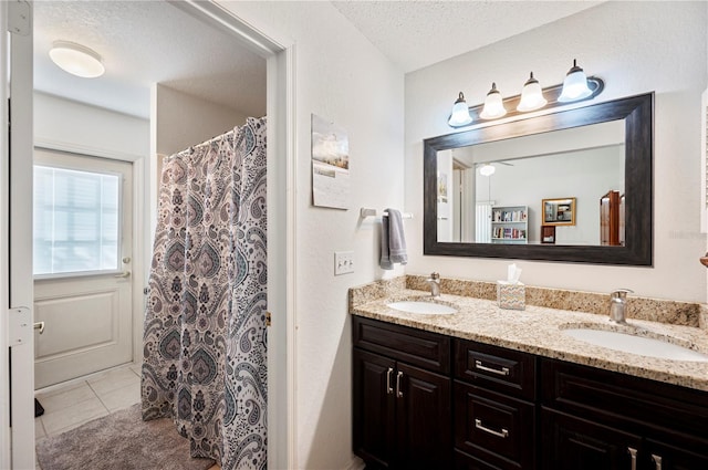 bathroom with double vanity, a sink, a textured ceiling, and tile patterned floors