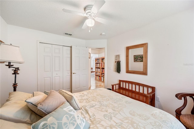 bedroom featuring a closet, visible vents, ceiling fan, and a textured ceiling