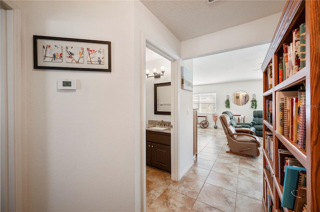 hallway featuring light tile patterned floors, a textured ceiling, and a sink