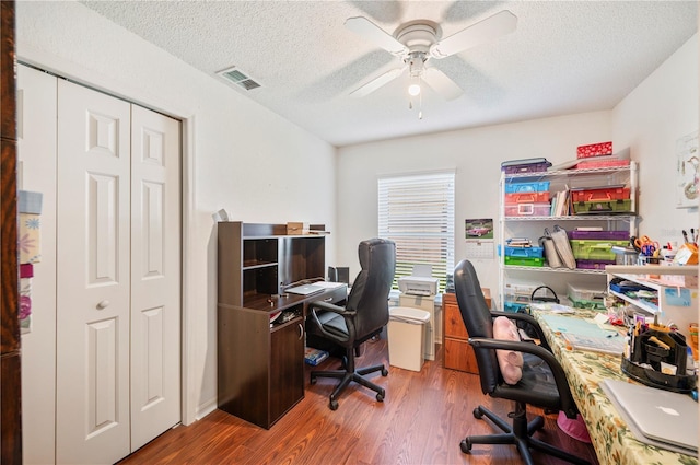 office area featuring ceiling fan, a textured ceiling, wood finished floors, and visible vents