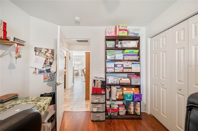 interior space with a closet, visible vents, a textured ceiling, and wood finished floors