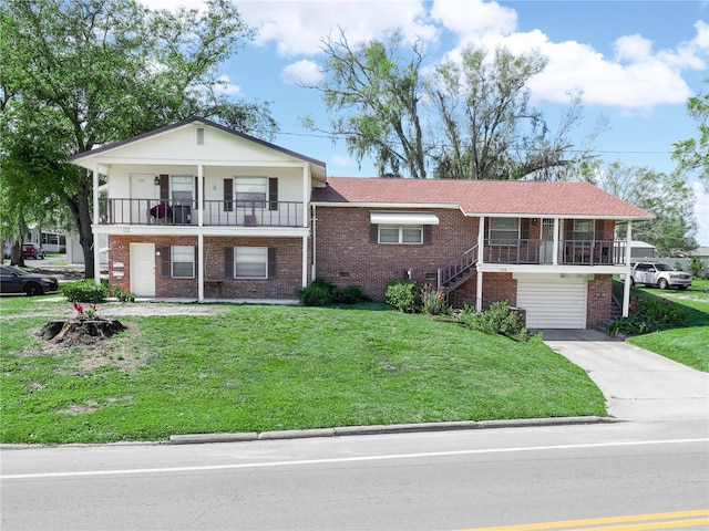 split level home with a balcony, a garage, brick siding, driveway, and a front yard