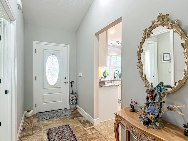 entrance foyer with baseboards, stone finish floor, and a healthy amount of sunlight