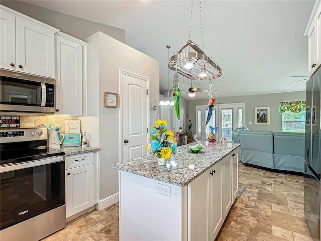 kitchen featuring stainless steel appliances, stone finish floor, white cabinetry, and tasteful backsplash