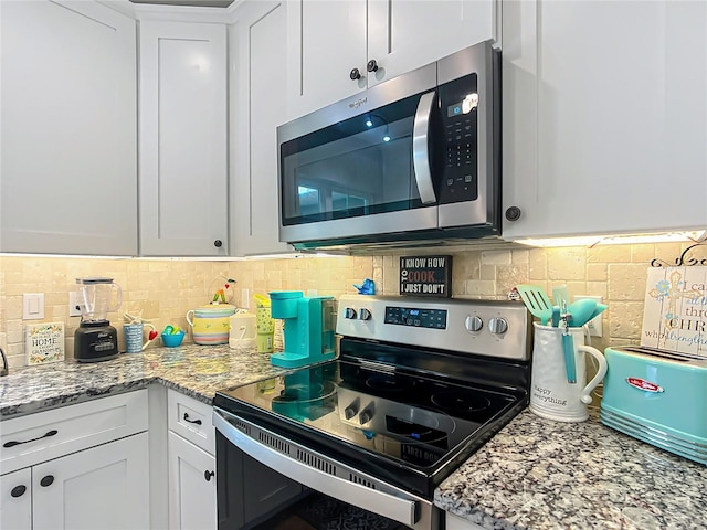 kitchen with white cabinets, light stone countertops, stainless steel appliances, and backsplash